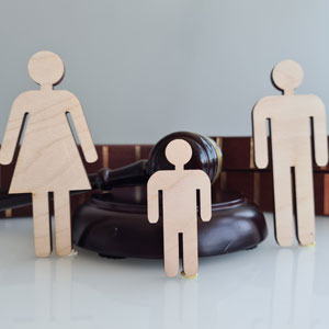 Wooden family figures and gavel, symbolizing custody disputes.